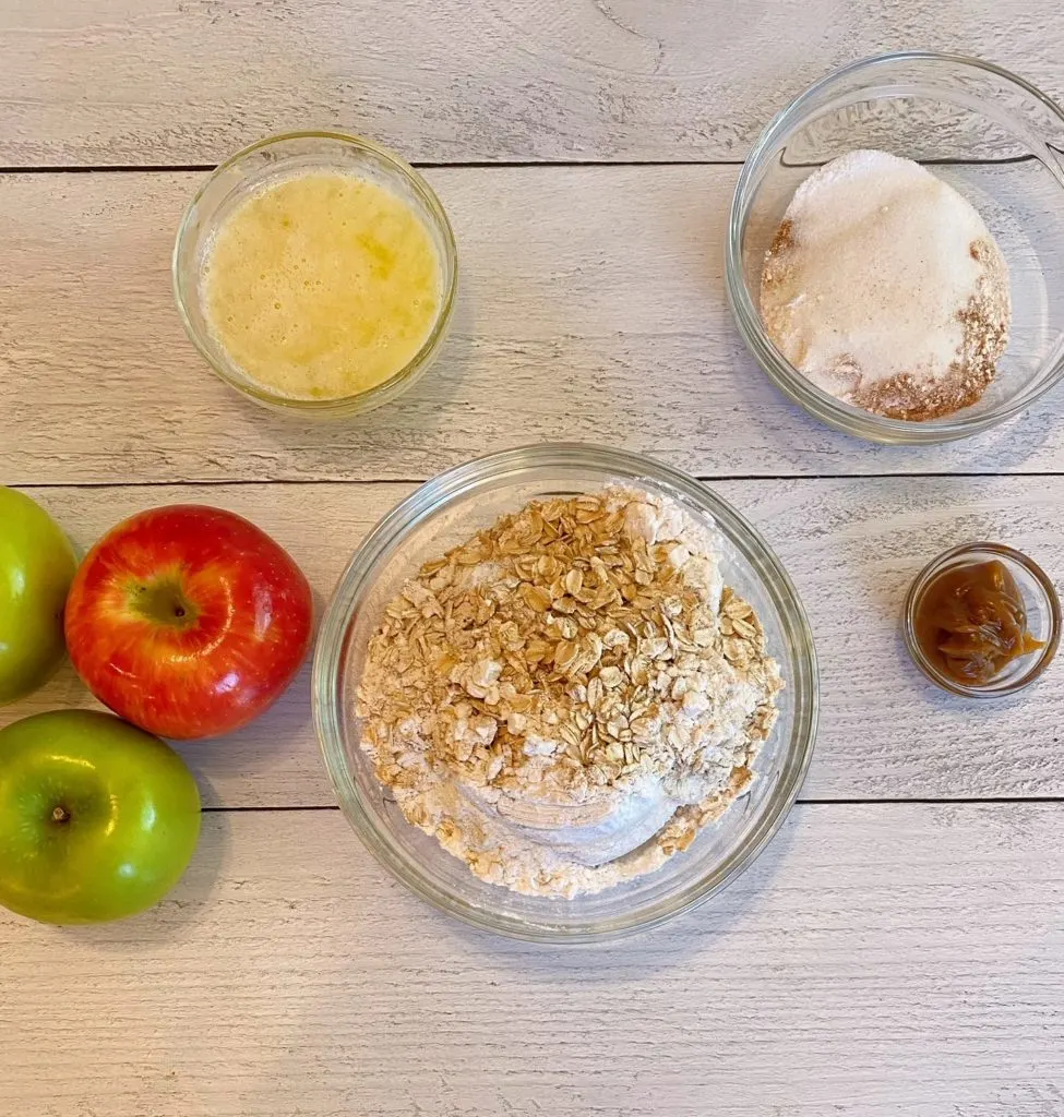 Ingredients on a white table for Caramel Apple Crisp. 