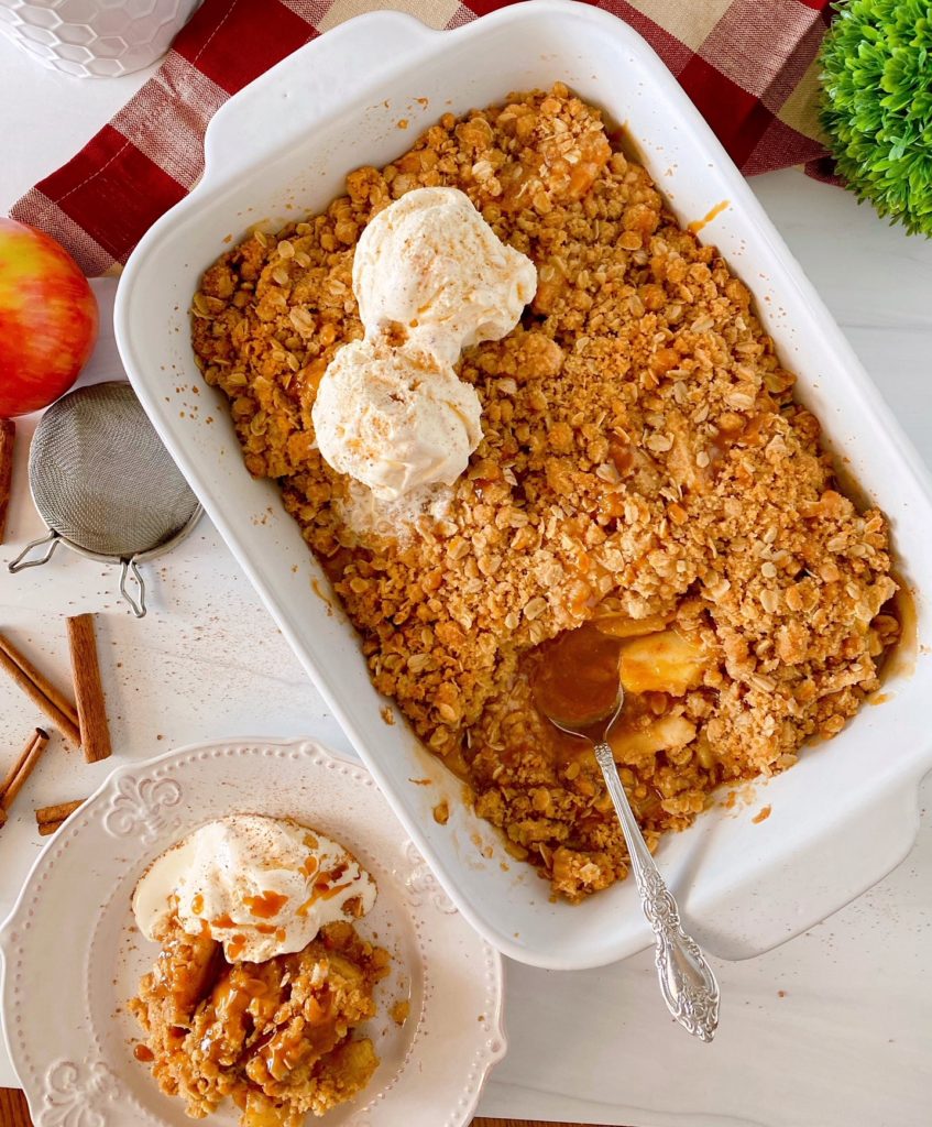 Easy Apple Crisp in a white baking dish with a serving on the side topped with vanilla ice cream.