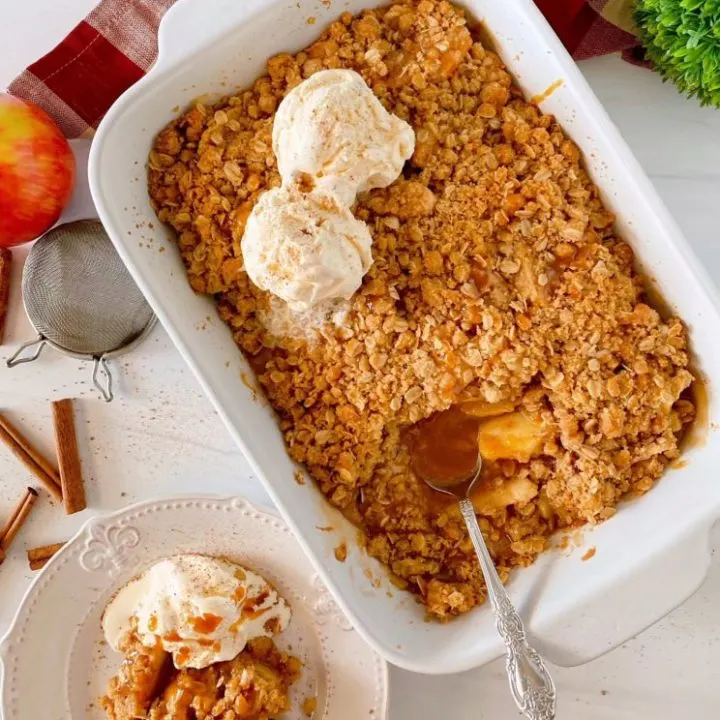 Easy Apple Crisp in a white baking dish with a serving on the side topped with vanilla ice cream.