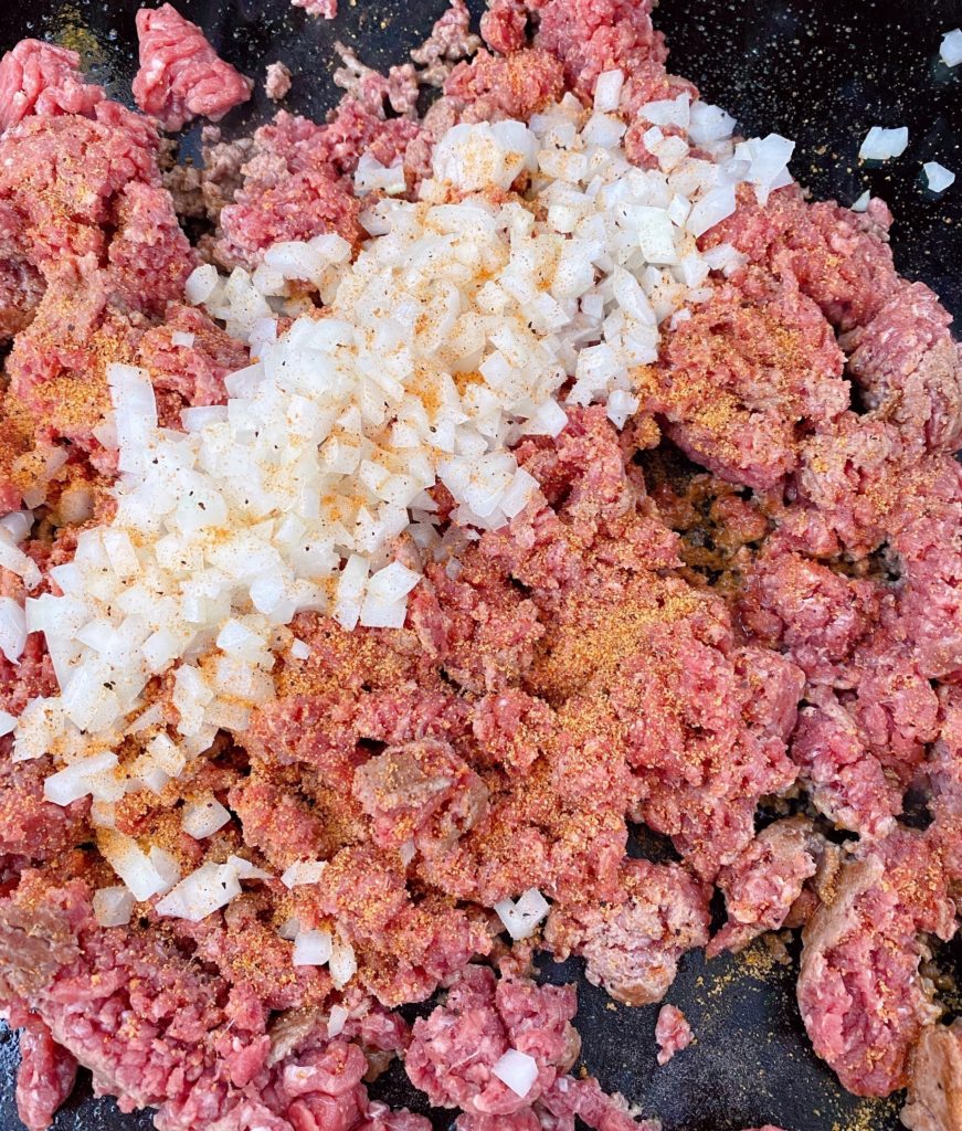 Ground beef, onions, and seasonings on hot griddle.