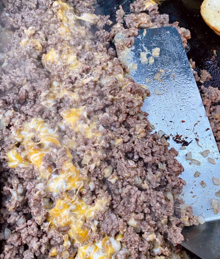 Stirring cheese into cooked ground beef.