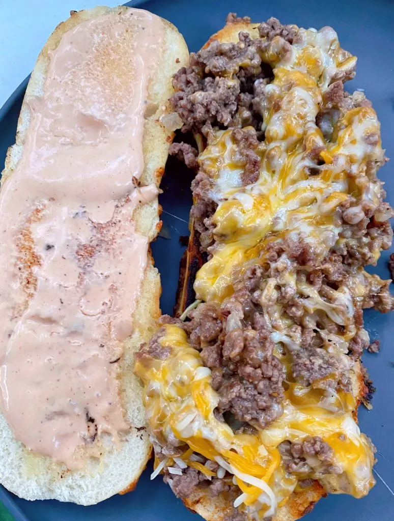 Bun with sandwich spread and one half loaded with loose meat.