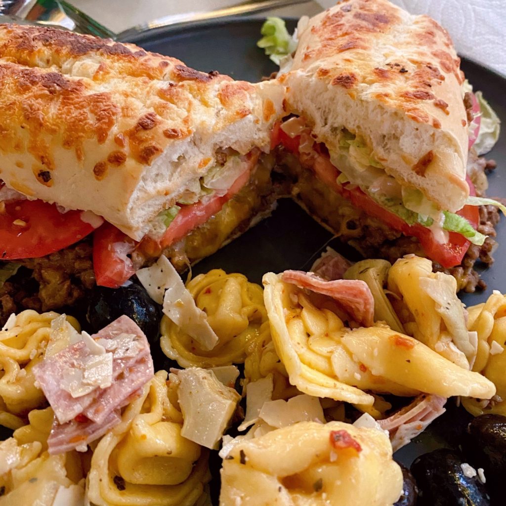 Loose Meat Sandwich cut in half with a serving of tortellini olive salad. o