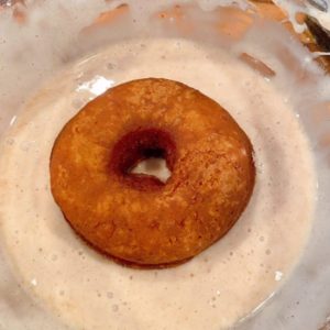 Donut being dipped in glaze