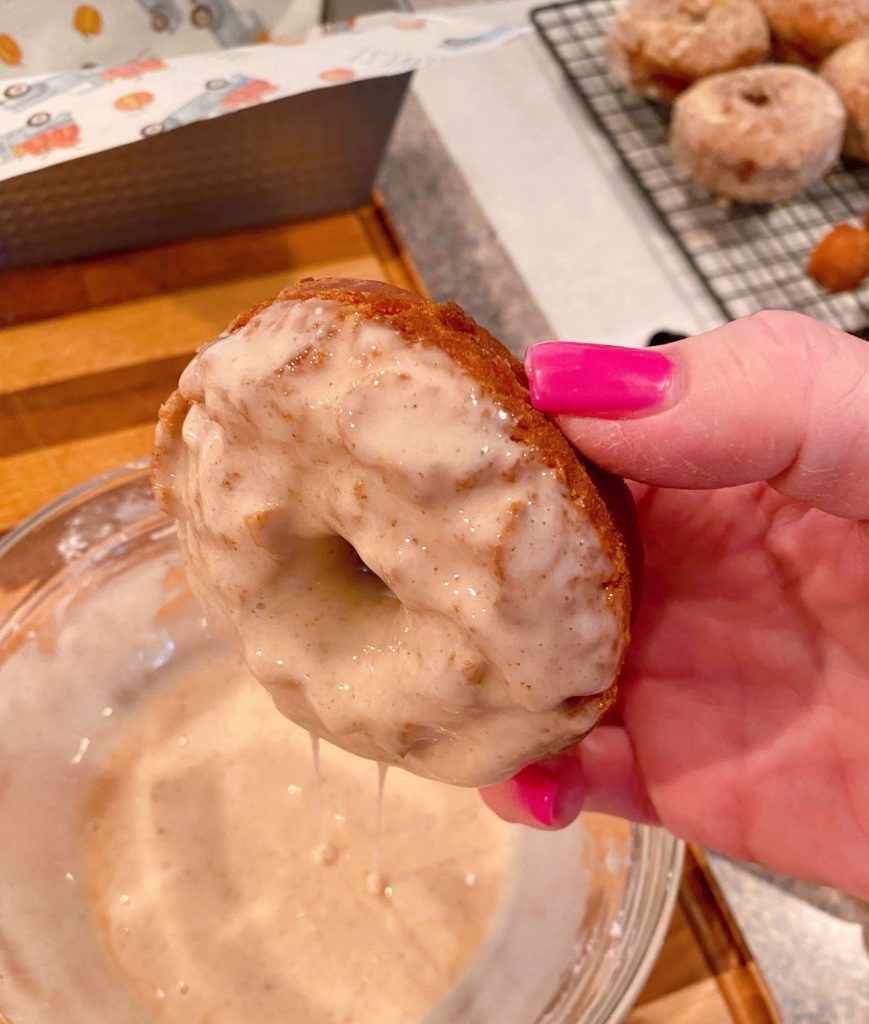 Donut being dipped in glaze.