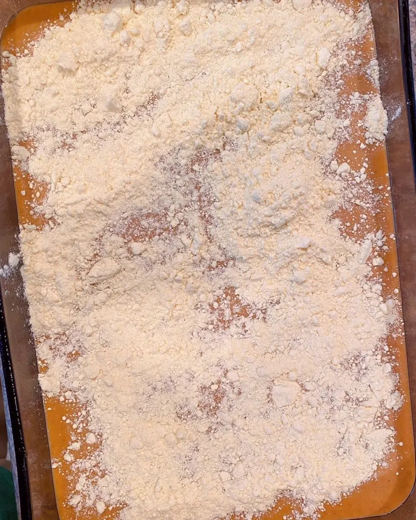 Pumpkin pie filling in baking dish sprinkled with cake mix.