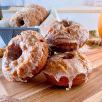 Pumpkin Spice Donuts on a cutting board with glaze dripping down them.