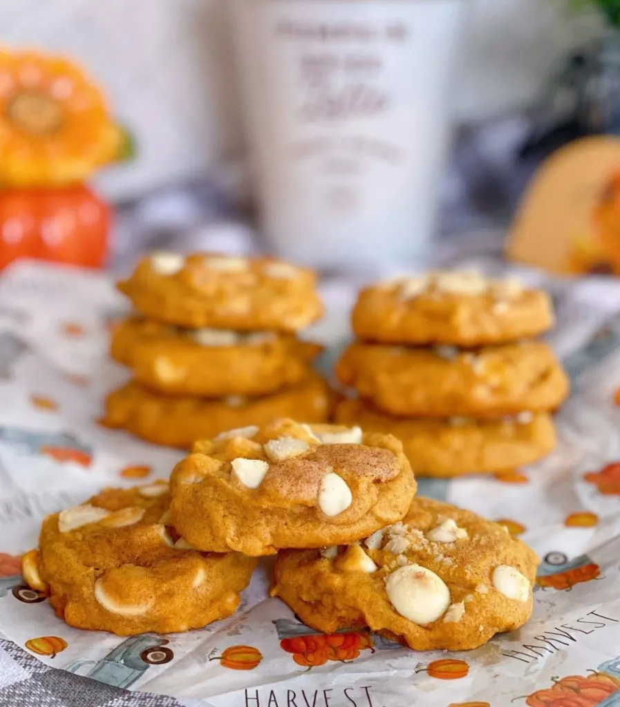 Stacks of Pumpkin White Chocolate Macadamia Nut Cookies on a Fall piece of paper.n
