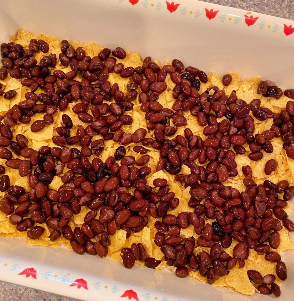 Sprinkled black beans over taco shells in casserole dish.