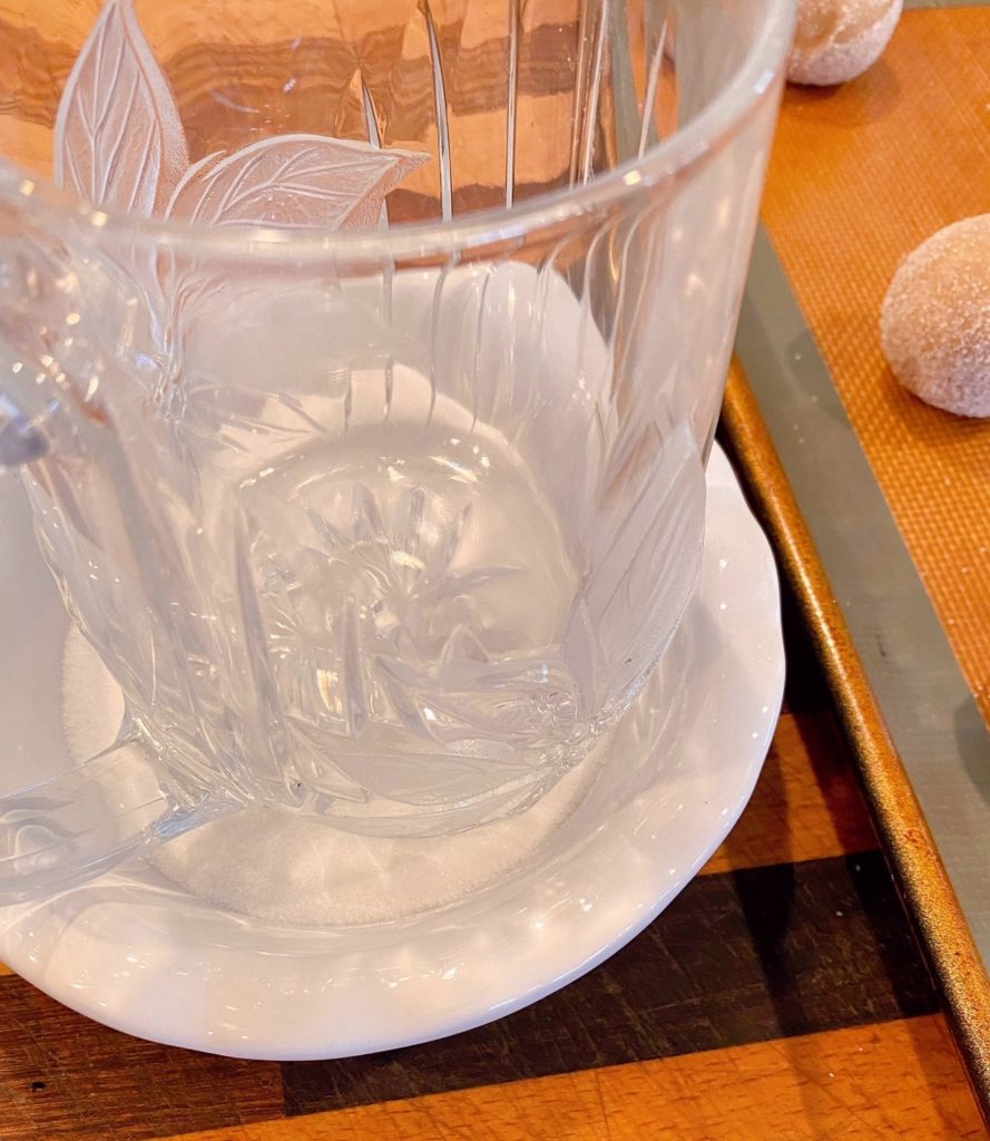 Cookies being flattened with texture glass dipped in sugar.