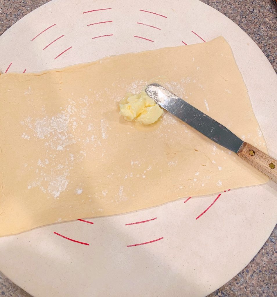 Spreading butter over crescent sheet of dough.