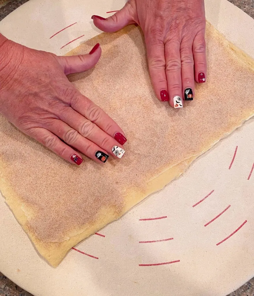 Patting cinnamon sugar into the crescent dough.