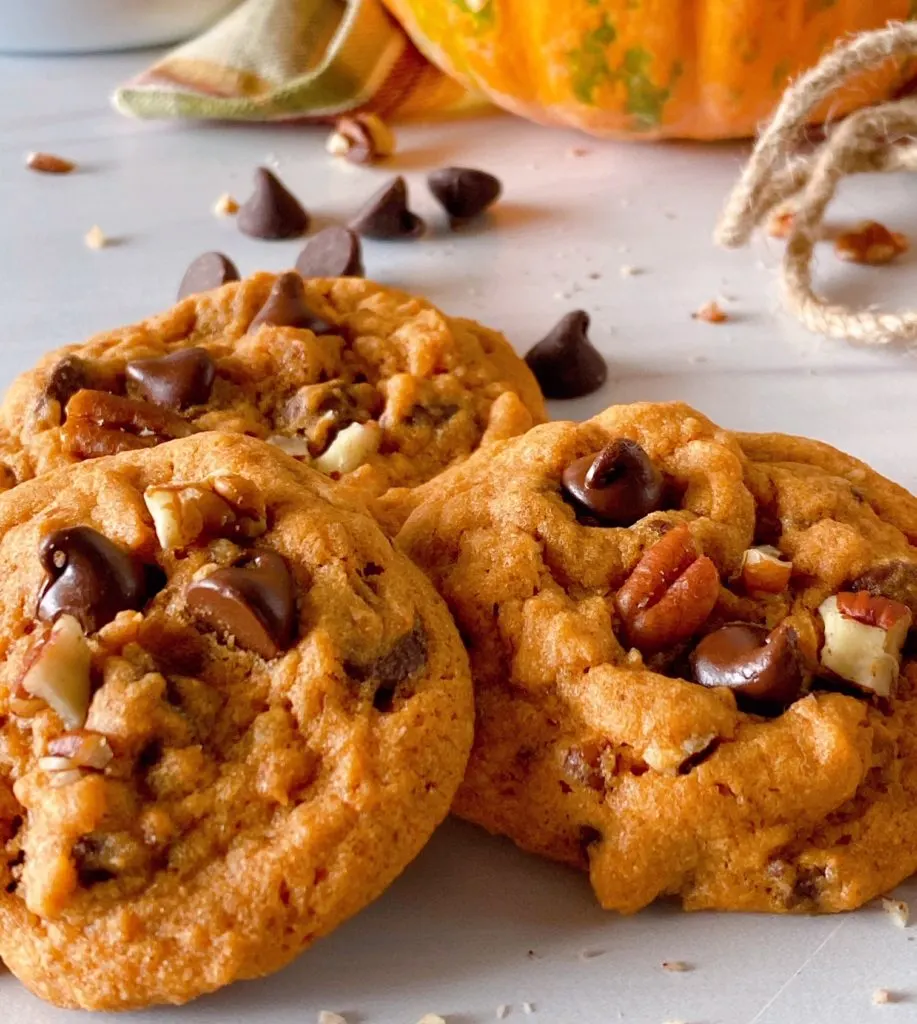 Pumpkin Chocolate Chip Cookies in a stack on a white counter.