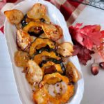 Roasted Acorn Squash with Pears on a long platter sprinkled with pecans.