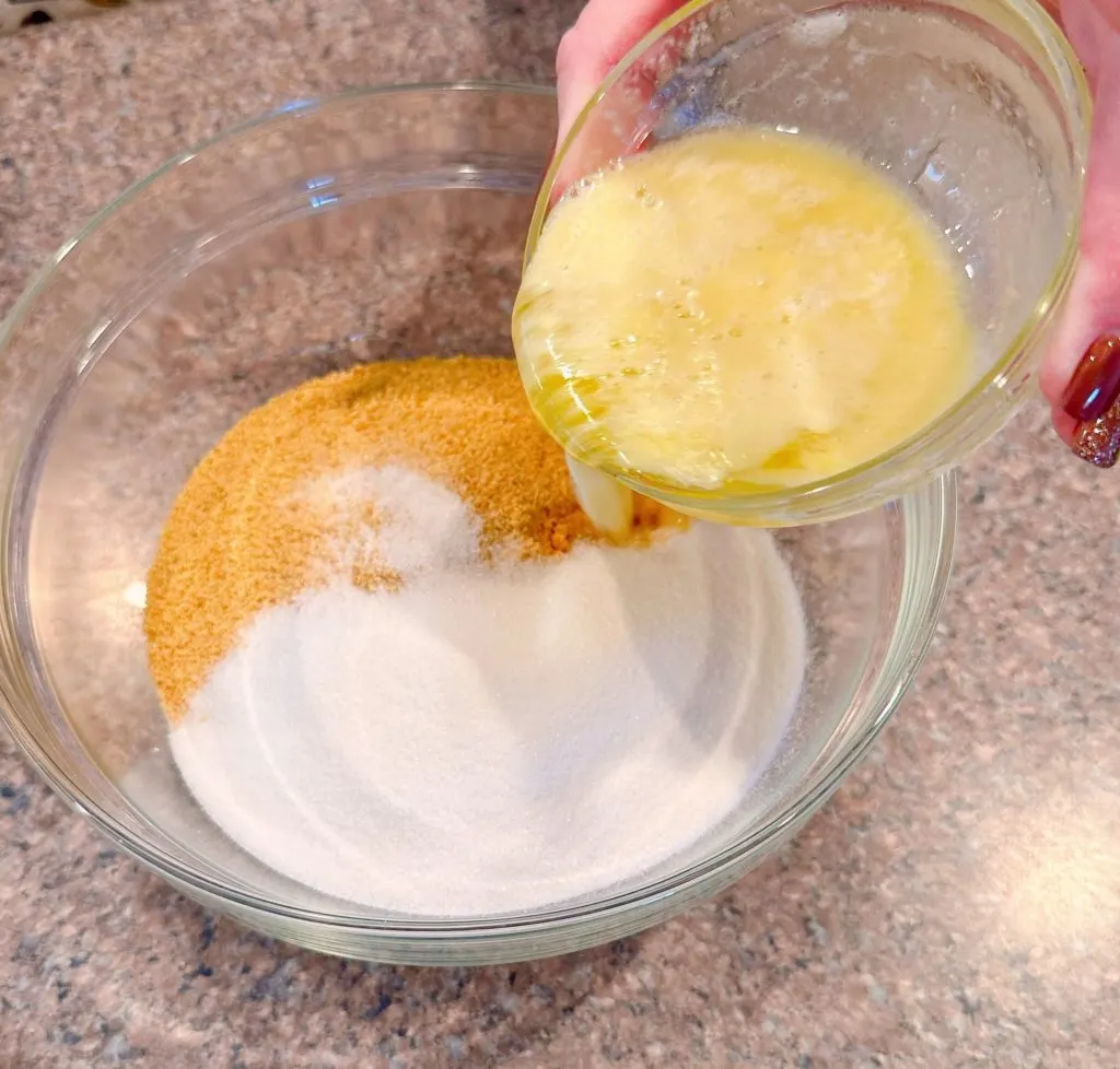 Adding sugar and melted butter to graham cracker crumbs in a large bowl for crust.