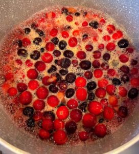 Blueberries, Cranberries, Orange Juice, sugar, and lemon juice in a large sauce pan boiling on the stove top.
