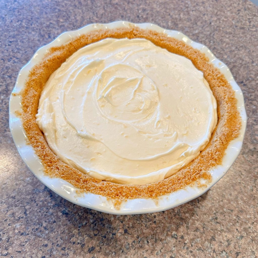 Cream cheese filling spread evenly in graham cracker pie crust.