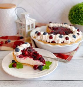 Cranberry Blueberry Cream Cheese Pie slice on a white plate with whole pie in the background.