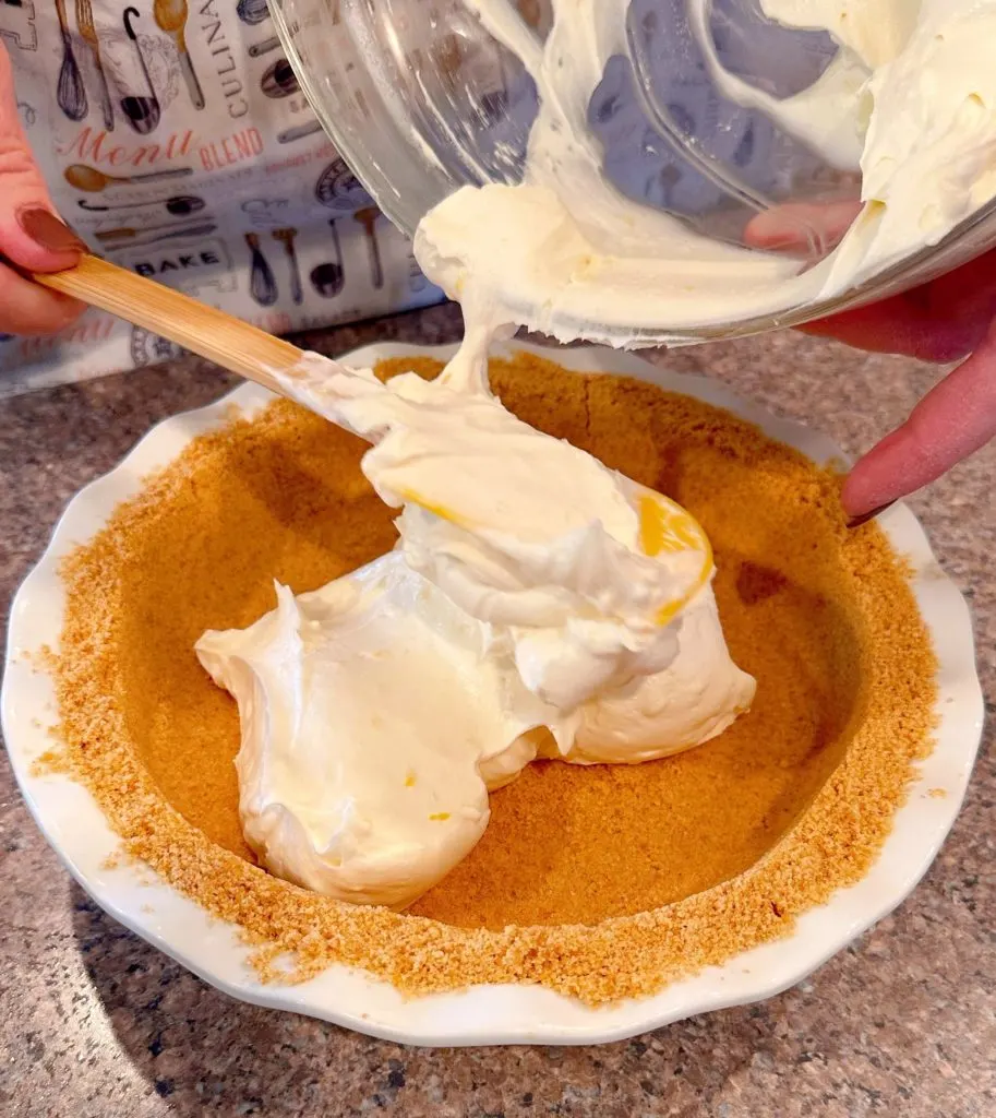 Adding Cream Cheese filling to chilled graham cracker pie crust.