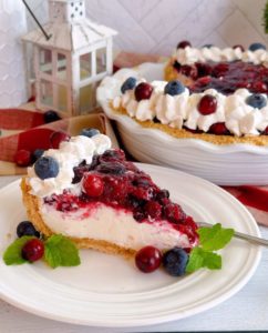 Slice of Cranberry Blueberry Cream Cheese Pie on a plate with the entire pie in the background.