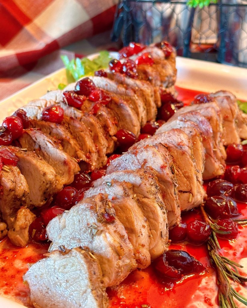 Pork Tenderloin on a serving platter with cranberry sauce.