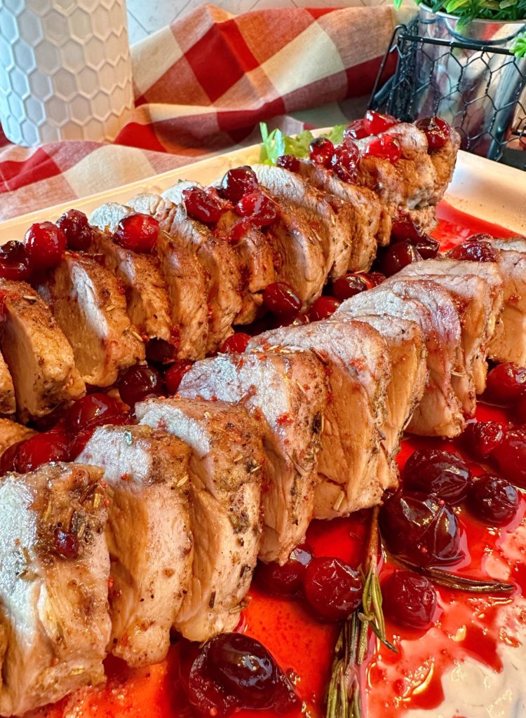 Roast Pork Tenderloin with Cranberry Sauce on a white serving platter.