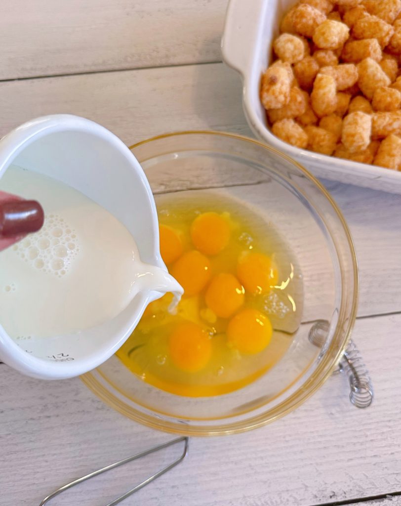 Eggs in a mixing bowl with milk being added.