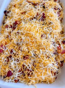 Adding bacon, ham, and cheese to Tater Tot Casserole.