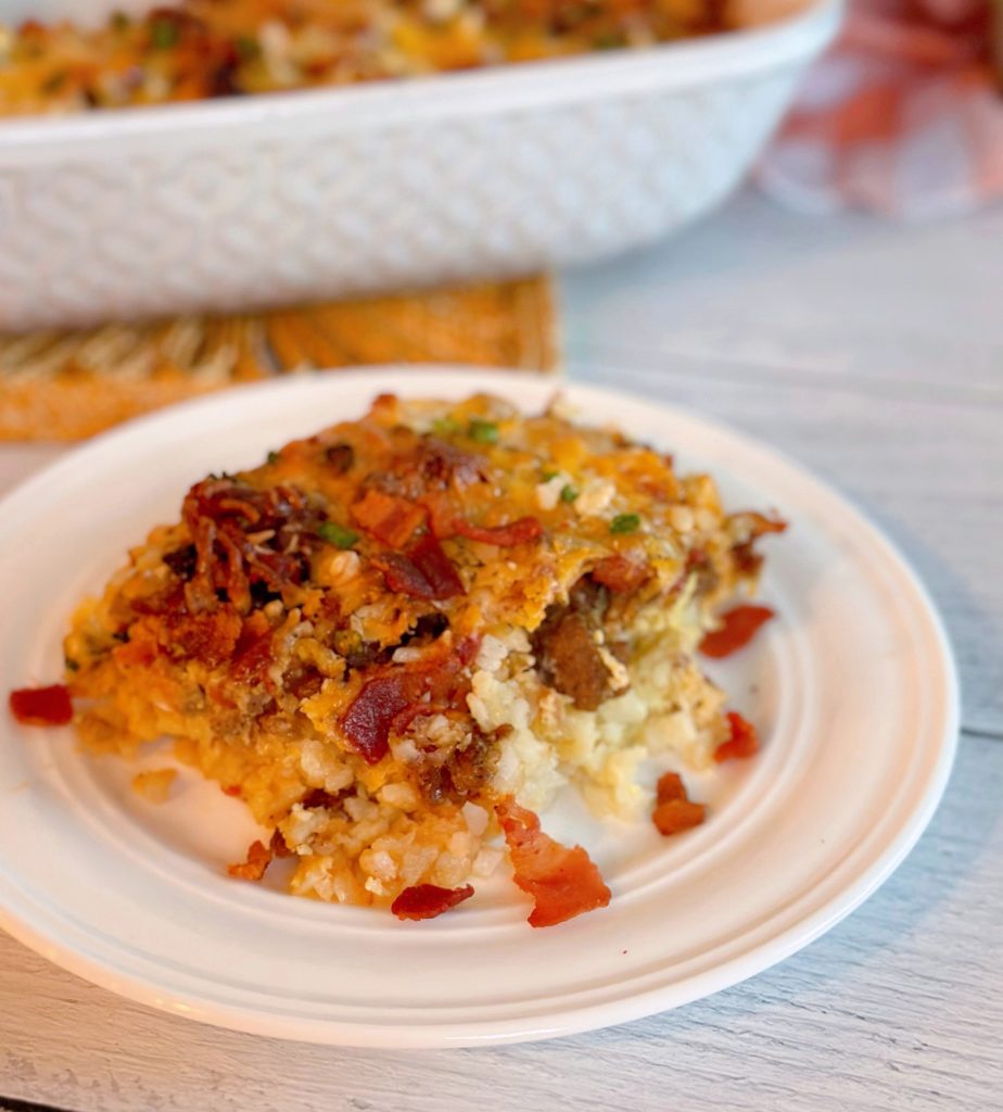 Breakfast Tater Tot Casserole on a white plate with the casserole dish in the background.