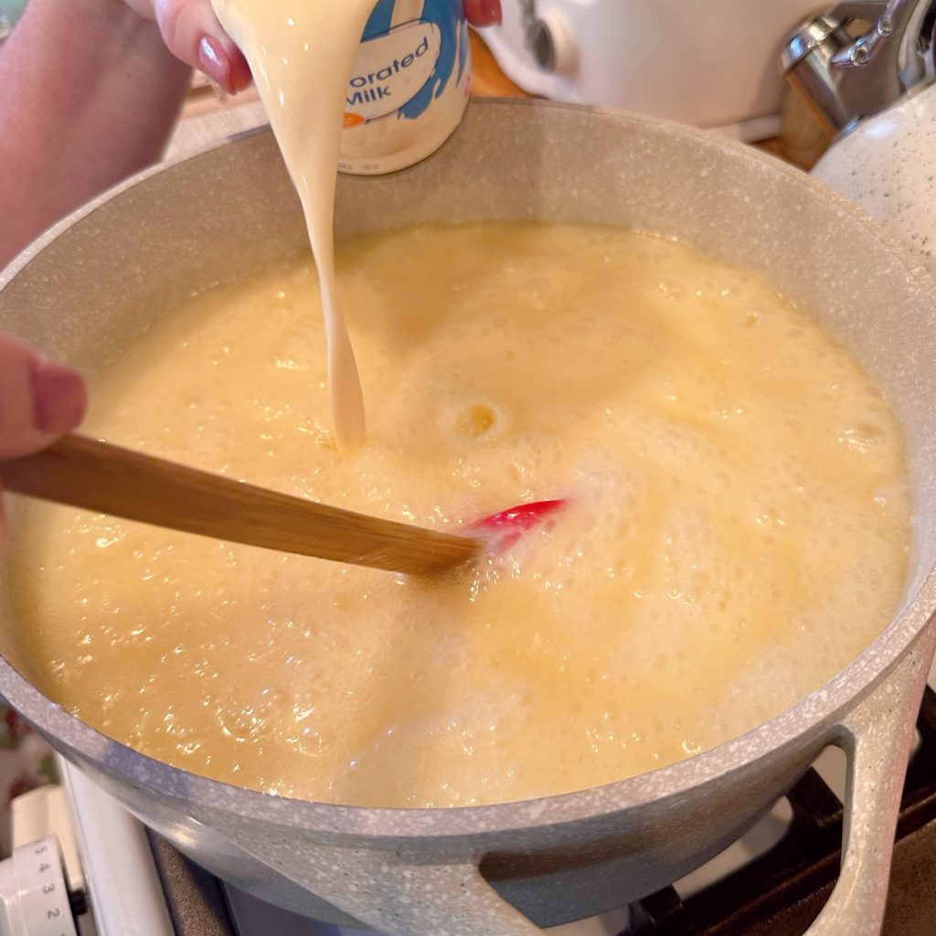 Adding evaporated milk to caramels.