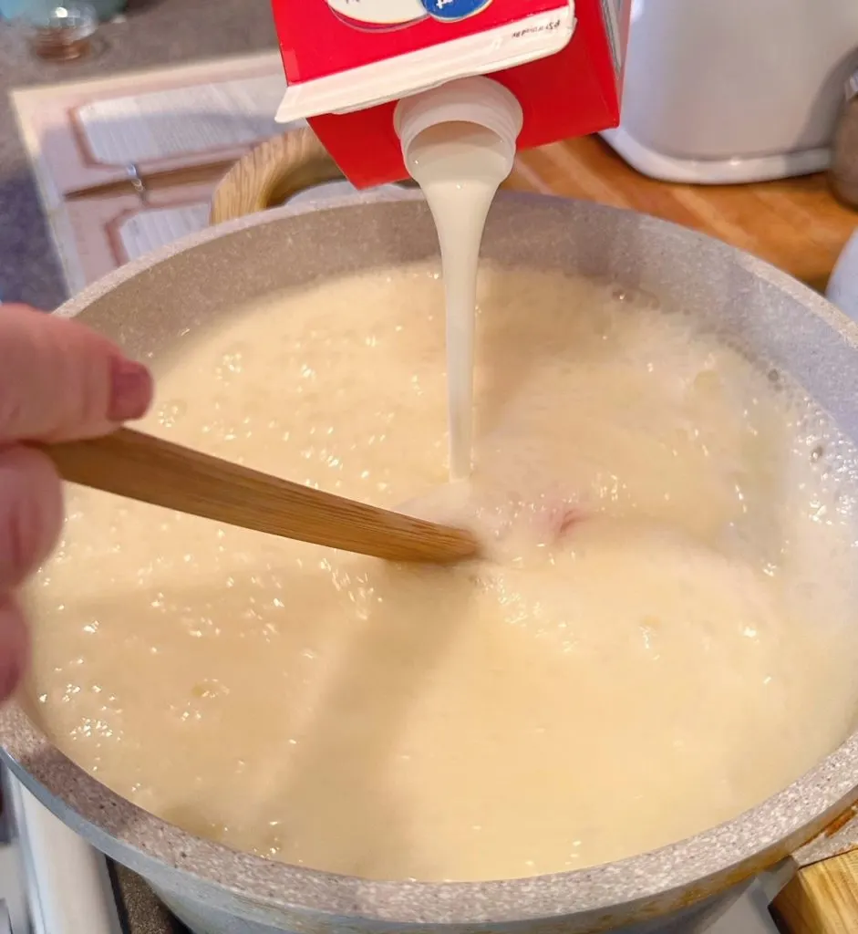 Adding remaining cream to boiling sugars.
