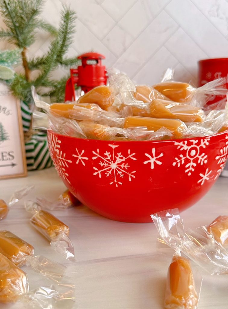 Homemade Caramels in a bright red candy dish on the kitchen counter.