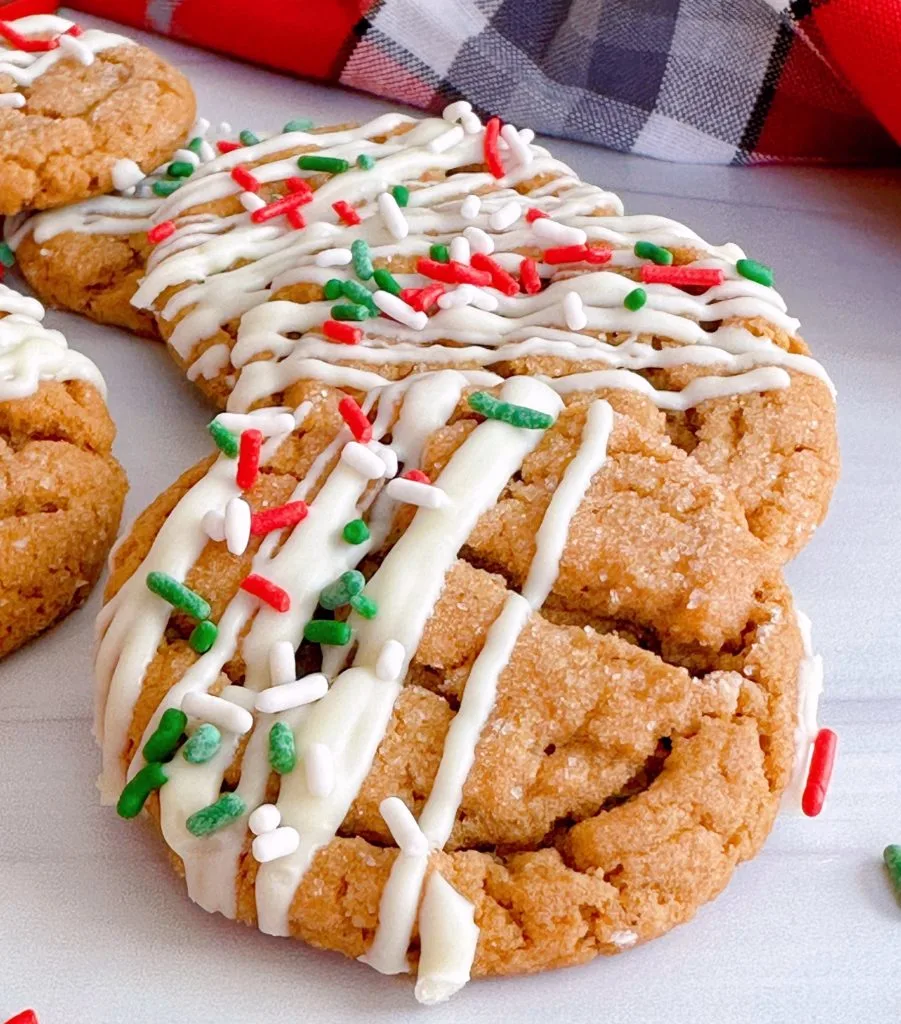 Gingersnap cookies with festive sprinkles ready to eat on a white counter.