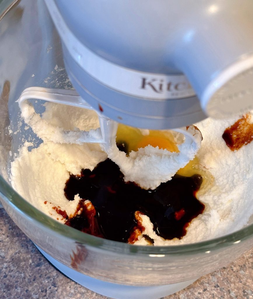 Adding egg and molasses to creamed sugar and shortening mixture in mixing bowl.