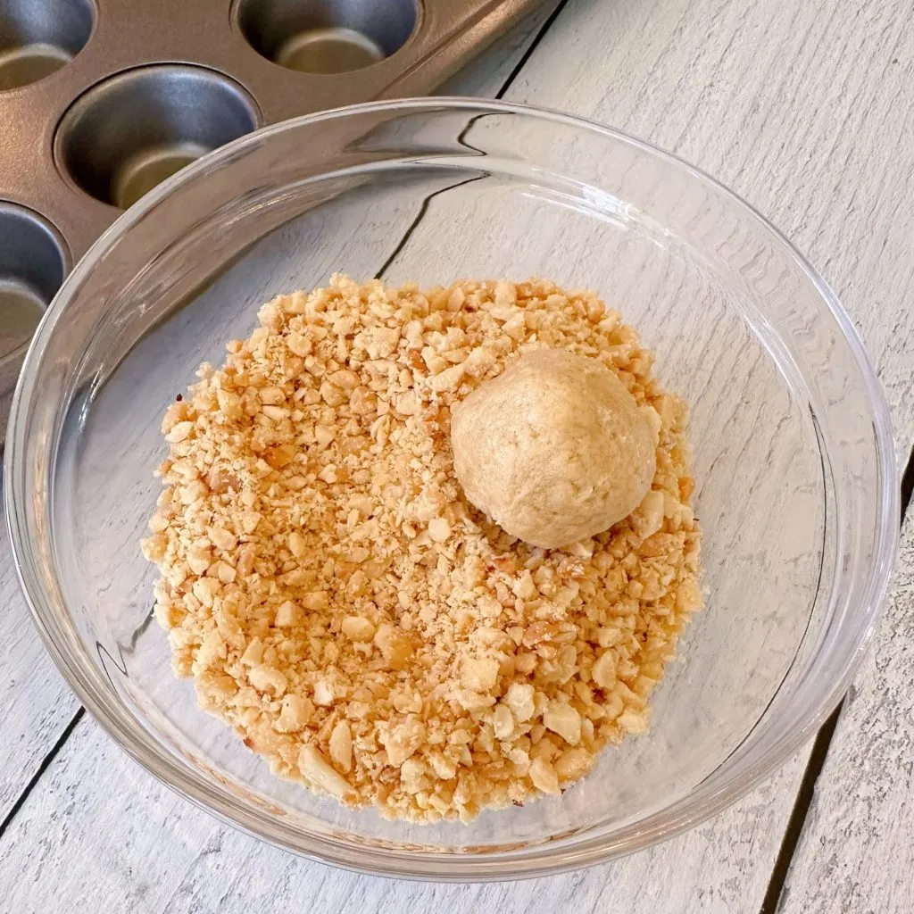 Rolling Peanut Butter Cookie dough in chopped peanuts.