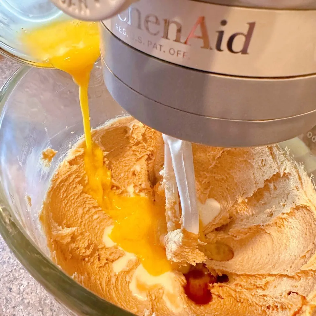 Adding wet ingredients into blended sugars in mixing bowl.