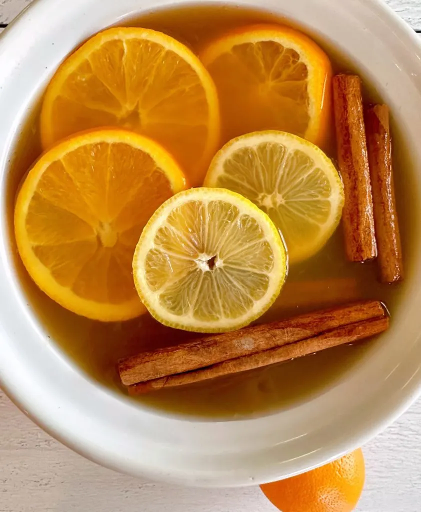 Adding Orange and Lemon Slices to Hot Apple Cider in the slow cooker.