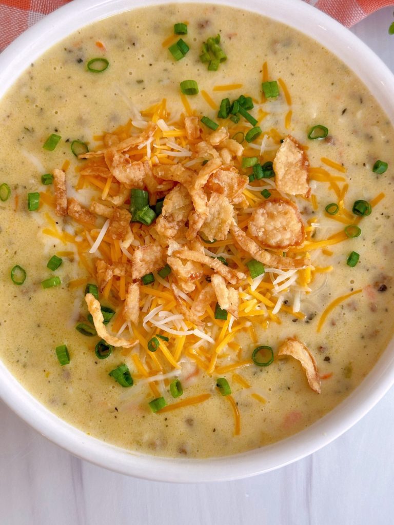 Overhead shot of Cheeseburger soup with toppings of crispy onion rings and green onions.