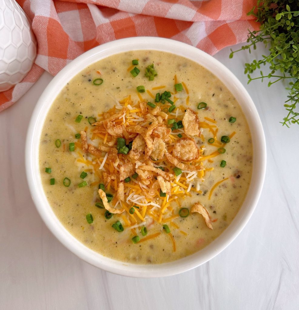 Cheeseburger Soup in a white bowl on a marble kitchen counter top with a napkin in the background.