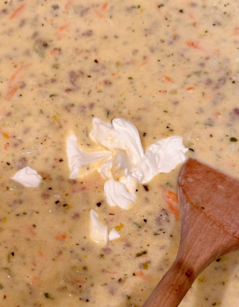 Adding sour cream to the soup as a final touch.