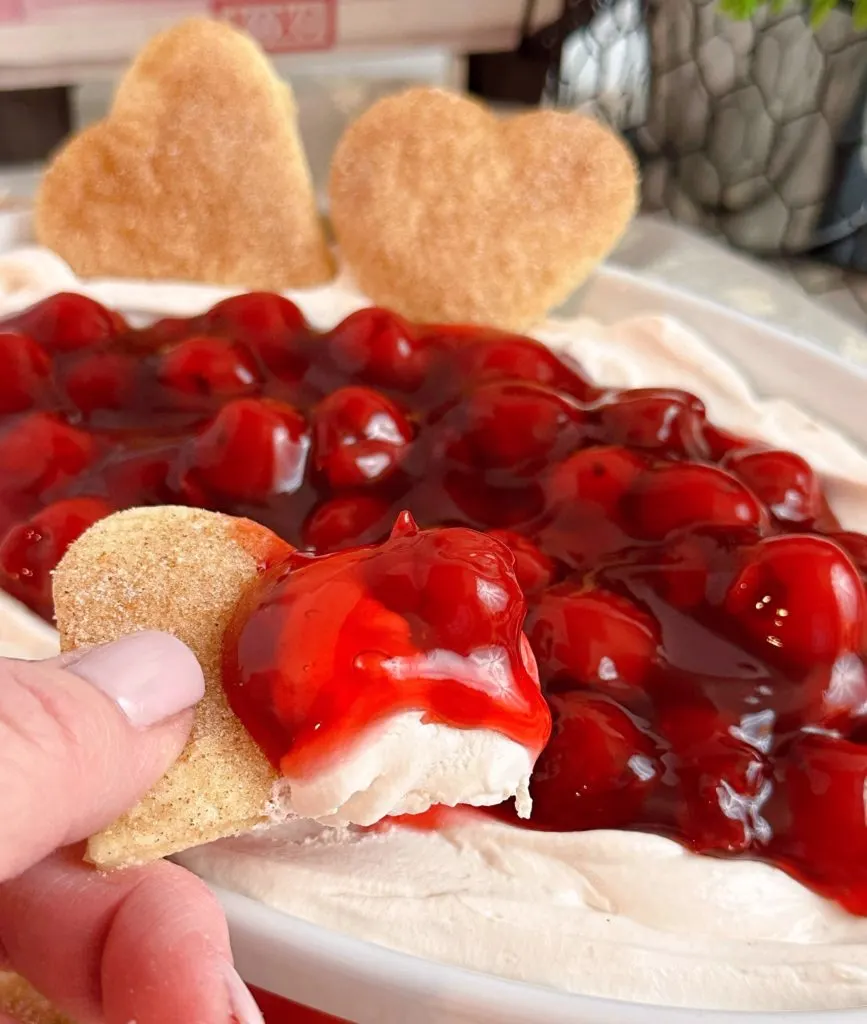 Dipping a pie scrap heart into the cherry cloud fruit dip.