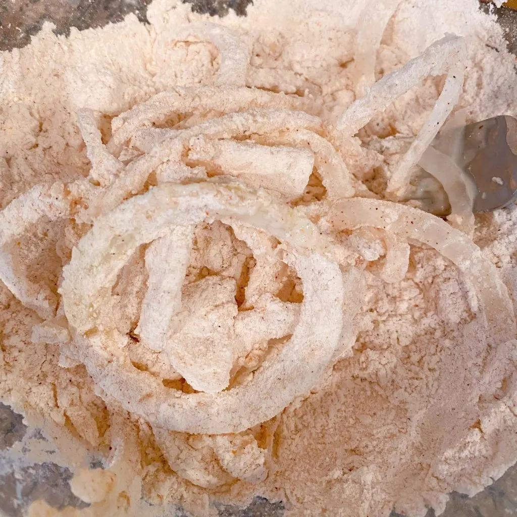 Onion rings coated with flour mixture ready to fry.