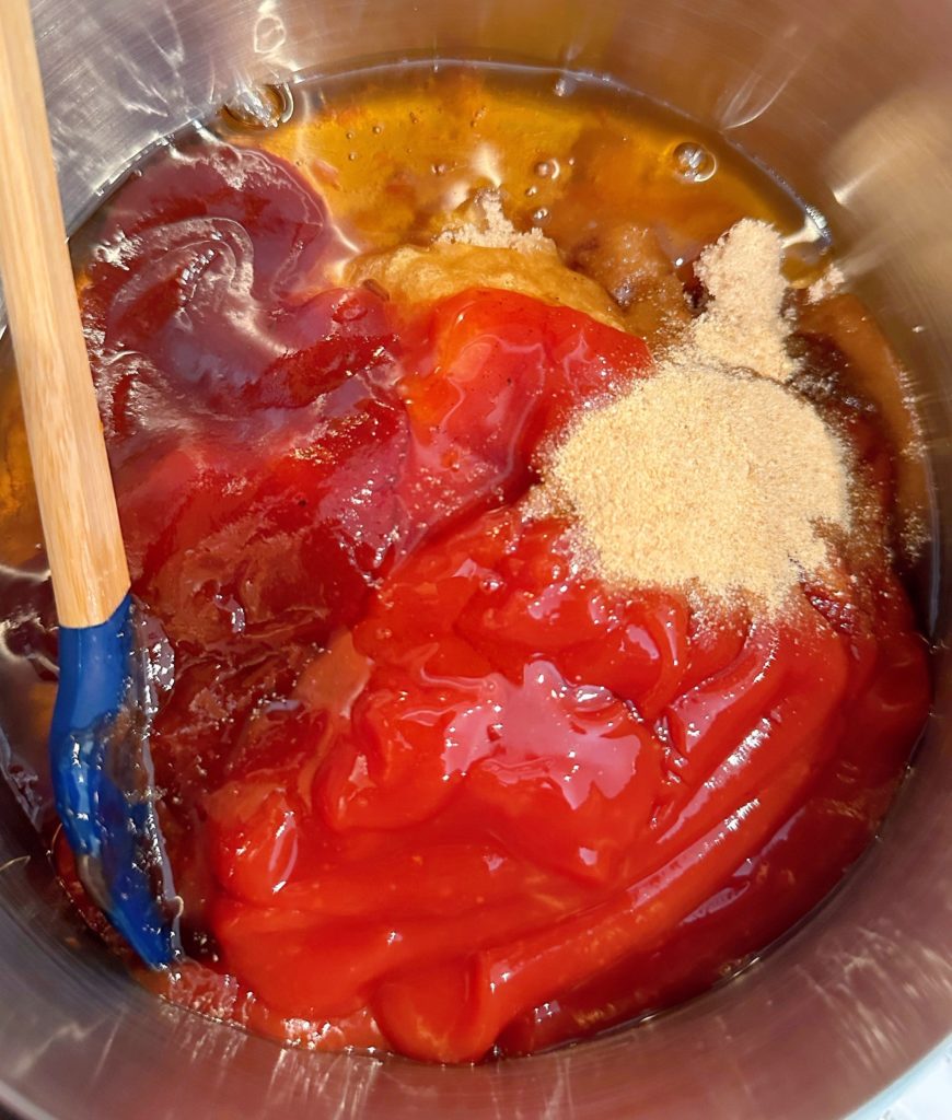 Ingredients for J. Dawg Special sauce in a medium sauce pan with silicone spatula cooking on stove.