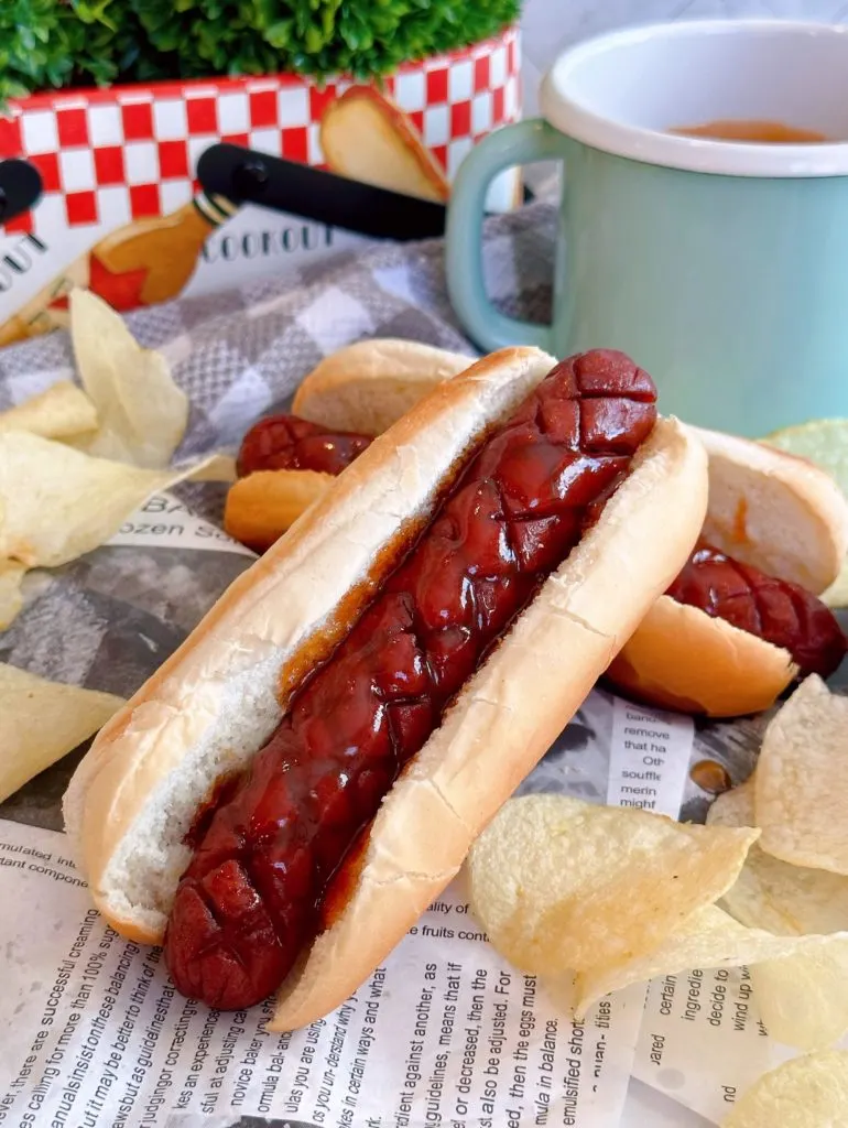 Stack of cooked J. Dawgs in buns with sticky sweet sauce.