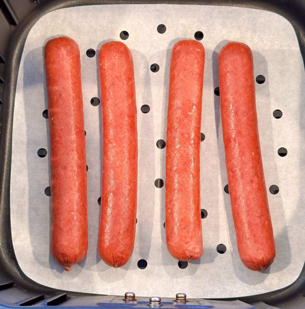 Prepared Hot Dogs on baking sheet in the air fryer tray.