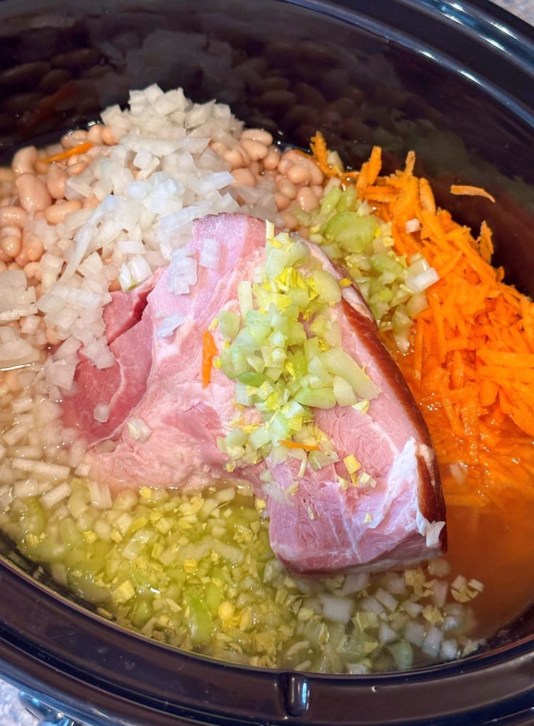 Addition of celery, carrots and onions to navy bean soup in the crock pot.