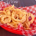 Crispy Onion Straws in a red burger basket with checkered paper.