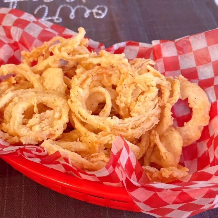 Crispy Onion Straws in a red burger basket with checkered paper.
