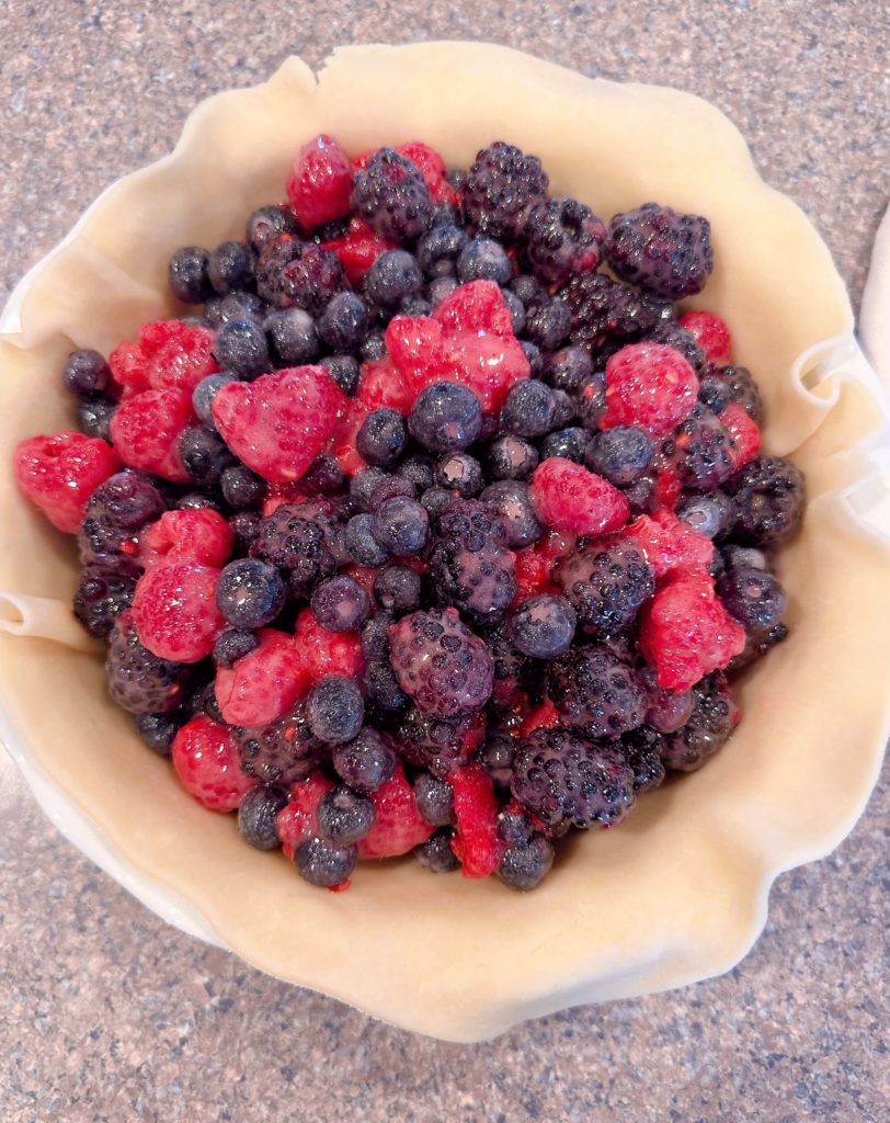 Adding the berry pie filling to the pie crust lined pie.