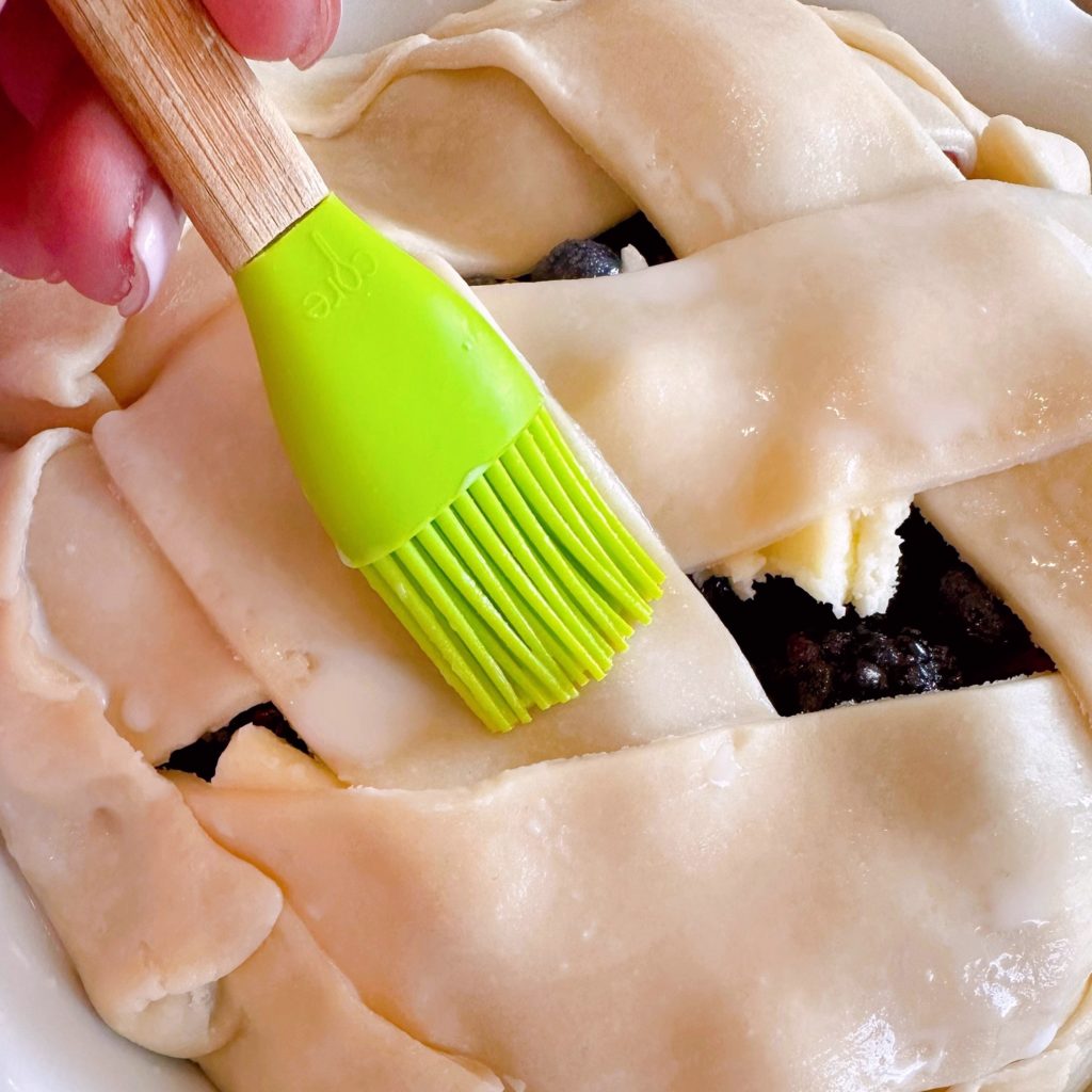 Brushing pie crust with milk.